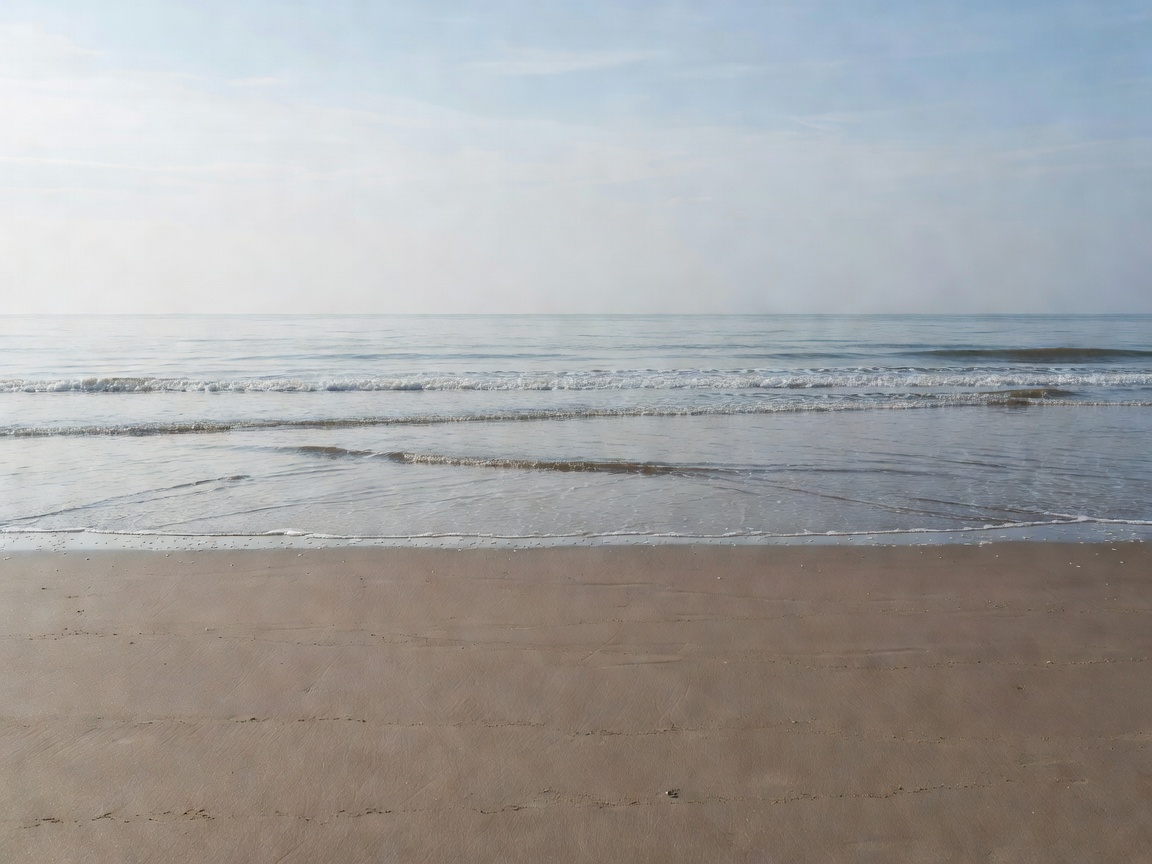 Empty sandy beach at low tide with gentle waves rolling in