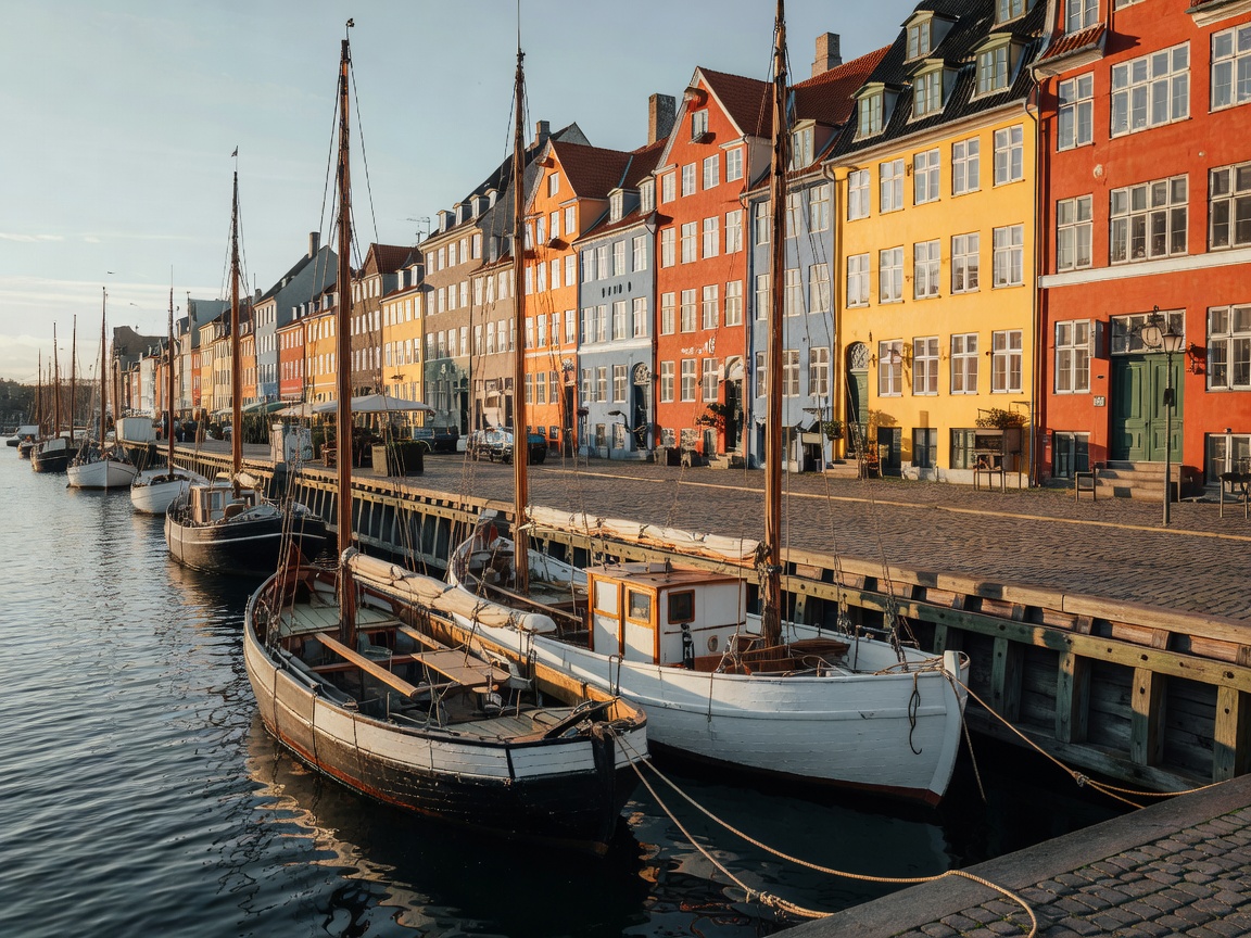 Historic Copenhagen harbour with wooden boats moored beside colourful facades