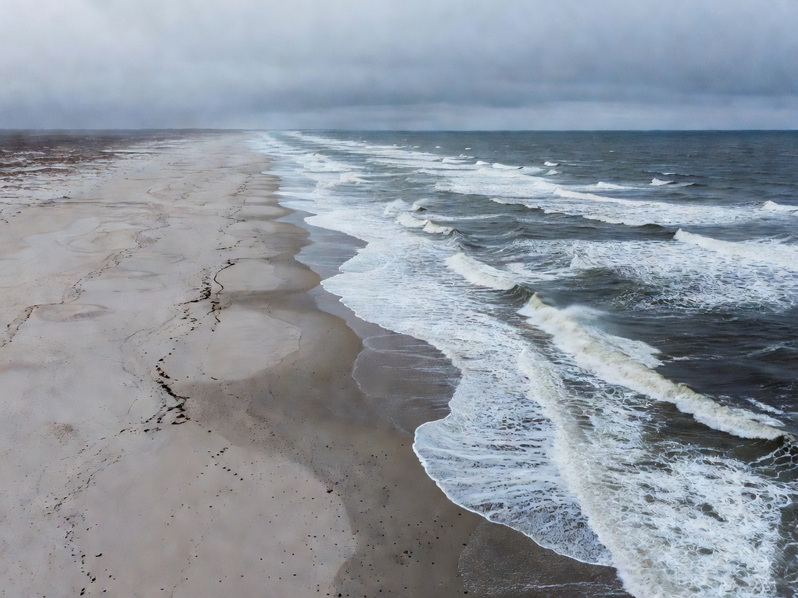 Open northern coastline with waves and broad sandy beach seen from above