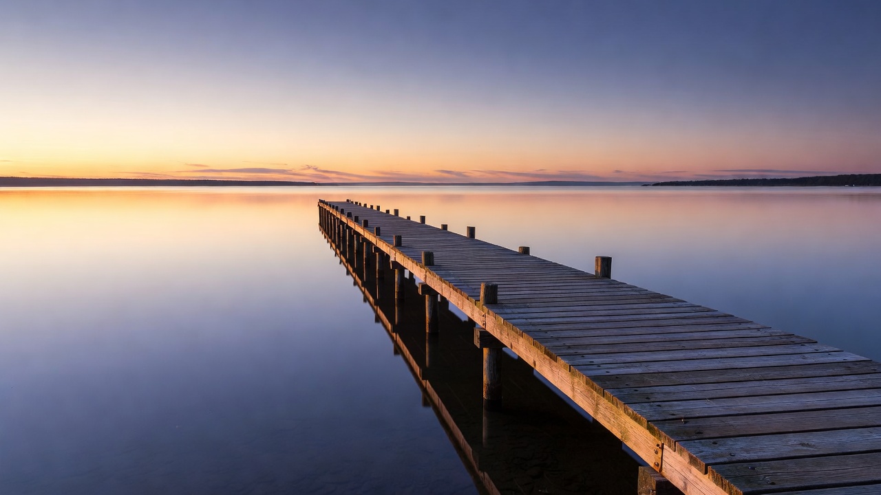 Wooden pier over still coastal water in the evening